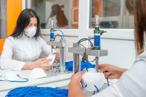 femmes travail à une machine pour le fabrication de médical masques avec nanofibre et souder boucles à leur avec ultrason. coronovirus et covid-19 la prévention photo