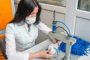 une femme travaux à une machine pour le fabrication de médical masques avec nanofibre et souder boucles à leur avec ultrason. coronovirus et covid-19 la prévention photo