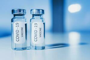 vaccin contre coronavirus covid-19 dans un ampoule sur une bleu Contexte fermer. photo