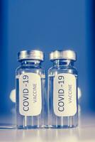 vaccin contre coronavirus covid-19 dans un ampoule sur une bleu Contexte fermer. photo