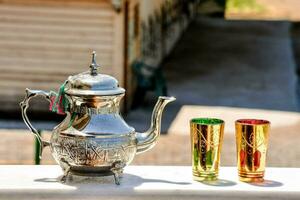 une argent thé pot et deux coloré tasses sur une table photo