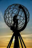 le Soleil ensembles derrière une globe sculpture photo