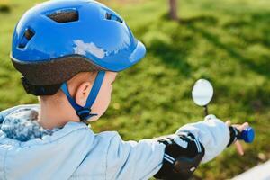 une enfant dans une casque monte une vélo sur une ensoleillé journée photo