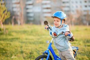 mignonne enfant est conduite une bicyclette sur une ensoleillé journée à le coucher du soleil photo