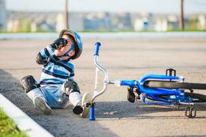 une petit enfant est tombée de une vélo sur le route, pleurs et en hurlant dans douleur. photo