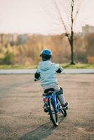 une enfant dans une casque monte une vélo sur une ensoleillé journée photo