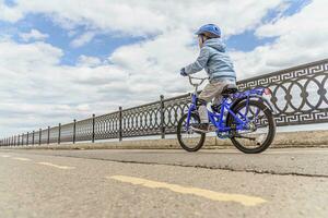 une enfant dans une casque et protection dans une bicyclette balade sur la nature dans le printemps photo