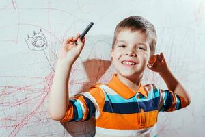 souriant enfant dessine sur le mur avec coloré des crayons photo