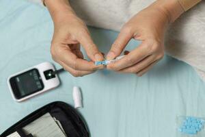 une femme main vérification sa du sang sucre niveau avec une glucomètre par se à sa maison. shotlistsanté photo