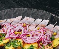 tranché hareng avec cuit patates et mariné oignons sur verre assiette photo