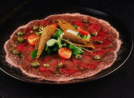 du boeuf carpaccio avec câpres sur noir assiette photo