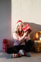 Jeune femme en bonnet de noel entouré de cadeaux photo