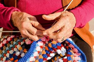 un plus âgée femme est tricot une coloré crochet couverture photo