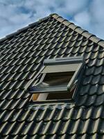 fenêtre de toit ouverte de style velux avec tuiles noires. photo