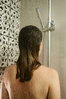 retour vue de femme prise une douche dans salle de bains photo