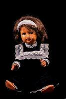 un vieux poupée avec une noir robe et blanc collier photo