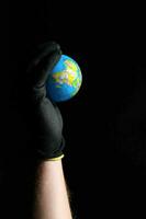 une la personne portant noir gants en portant en haut une petit globe photo