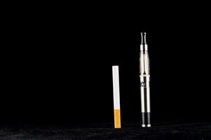 une cigarette et un électronique cigarette sur une noir Contexte photo