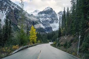 conduite sur autoroute avec des montagnes rocheuses dans la forêt d'automne au lac moraine, alberta photo