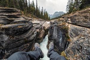 Voyageur suspendu les jambes sur le canyon de Mistaya dans la promenade des Glaciers photo