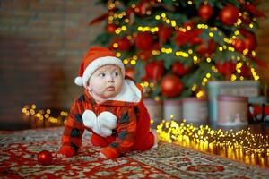 peu six mois vieux bébé habillé comme Père Noël claus. Contexte pour Noël carte. le enfant regards vers le bas à le endroit pour une inscription. photo