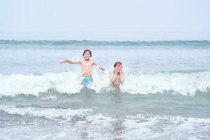 une garçon et une fille sont ayant amusement en jouant dans le mer. photo