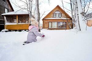 une famille construit une bonhomme de neige en dehors de blanc neige dans le Cour dans l'hiver. photo