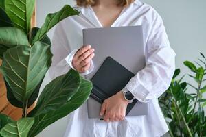 une femme détient une portable et graphique tablette contre une Contexte de verdure. photo