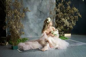 une Jeune blond femme dans un aéré rose robe avec une blanc enfant. printemps portrait de une femme. photo