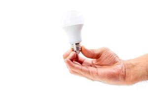 main humaine tenant une ampoule LED isolée sur fond blanc.