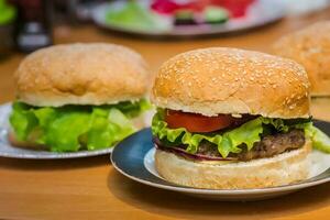 deux fait maison Burger avec tomate et du boeuf petit pâté, Frais garnitures sur entier grain artisan chignon sur cuisine table pour dîner photo