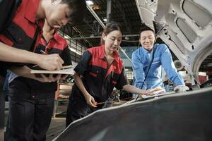 asiatique Masculin professionnel automobile superviseur conseille et inspecte une mécanicien ouvrier femme à propos liquide moteur pétrole à voiture garage, un service entretien, et réparer spécialiste métiers auto industrie. photo