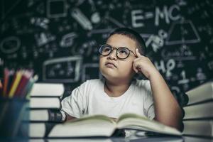les garçons avec des lunettes écrivent des livres et réfléchissent en classe photo