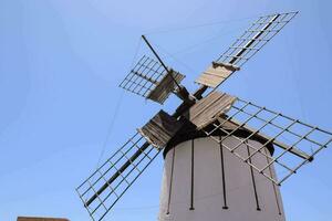 une Moulin à vent avec une en bois toit et une bleu ciel photo