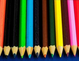une rangée de coloré des crayons sur une bleu Contexte photo