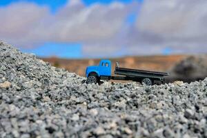 une bleu jouet un camion est séance sur Haut de une pile de gravier photo