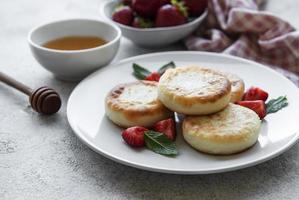 crêpes au fromage cottage, beignets de ricotta sur plaque en céramique avec fraise fraîche.