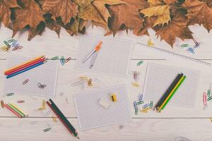 l'automne école Provisions sur une blanc en bois table avec l'automne feuilles photo