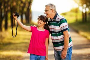 content petite fille et grand-père prise photo ensemble dans la nature