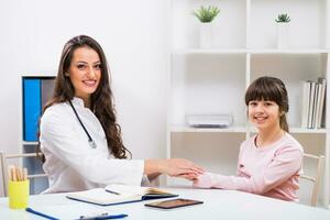 femelle médecin et enfant en portant mains à le médical Bureau photo