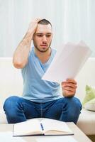 Jeune homme à la recherche à le sien document dans panique tandis que travail à le sien Accueil photo