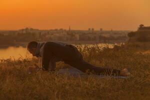 homme Faire yoga sur le coucher du soleil avec ville vue photo