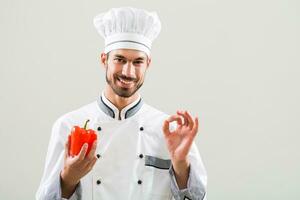 chef est montrant des légumes et D'accord signe sur gris Contexte photo