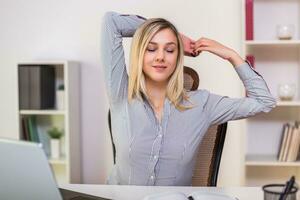 femme d'affaires élongation tandis que travail dans sa Bureau photo