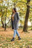 magnifique femme en marchant dans le parc et jouit dans l'automne. photo