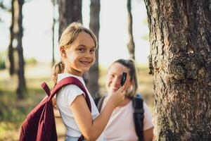 peu fille explorer avec grossissant verre la nature tandis que randonnée avec sa mère photo