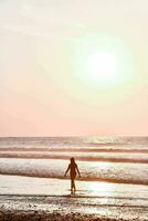 une homme en marchant sur le plage à le coucher du soleil photo