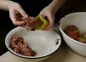 mains de le chef remplit le cloche poivrons avec haché Viande. étape par étape préparation . dîner . sélectif photo . processus cuisine .