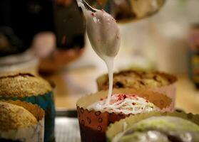 le chef mains orner le petits gâteaux avec glaçage sucre et tranches de sucre. Contexte flou, sélectif focus.high qualité photo