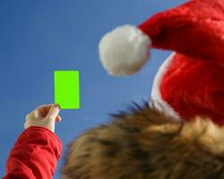 fermer de une femme main en portant une Vide vert cadeau carte.dans Père Noël chapeau et rouge veste. cadeau ou remise concept.haut qualité photo.sélective concentrer photo